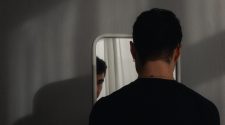 Homem olhando seu reflexo no espelho, ilustrando a transição de mentalidade e a mudança de comportamento na relação com o próprio corpo.